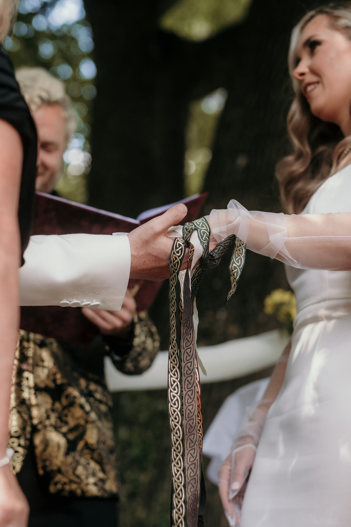 Die Hände des Hochzeitspaares sind verbunden durch die verzierten Bänder.