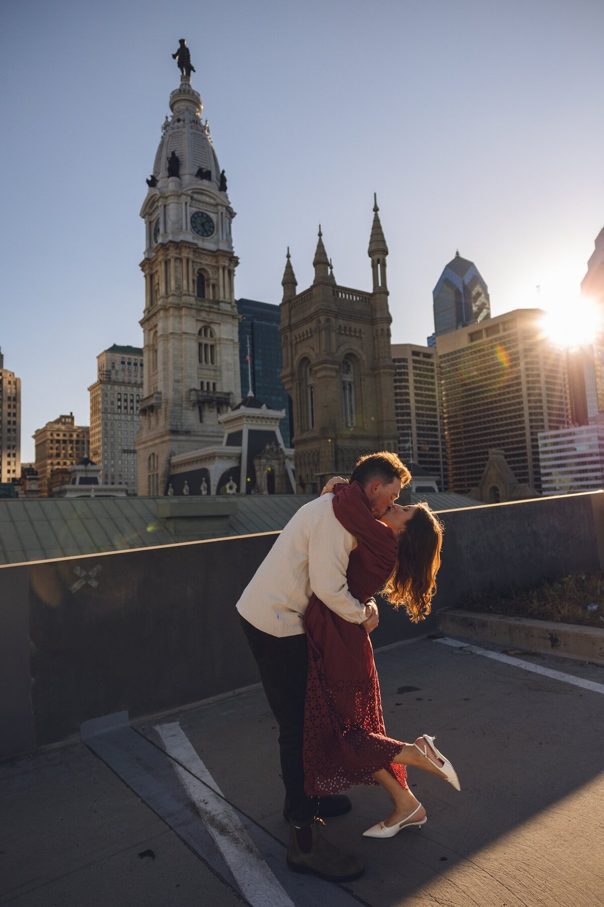 Rooftop sunset kiss framed by historic towers.