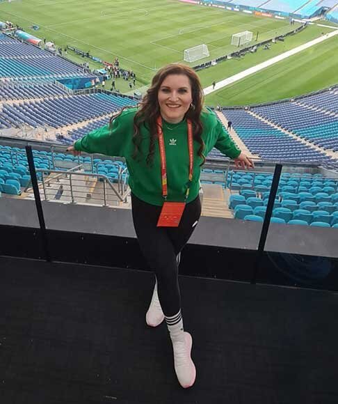 Female staff member poses with smile in front of empty stadium seats at FIFA Women’s World Cup venue