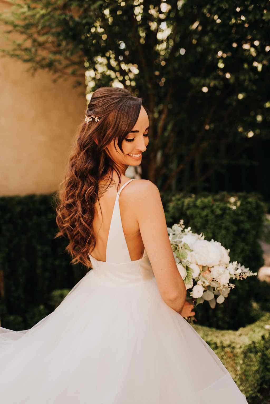 bride in long brown hair with sleeveless dress holding white wedding bouquet