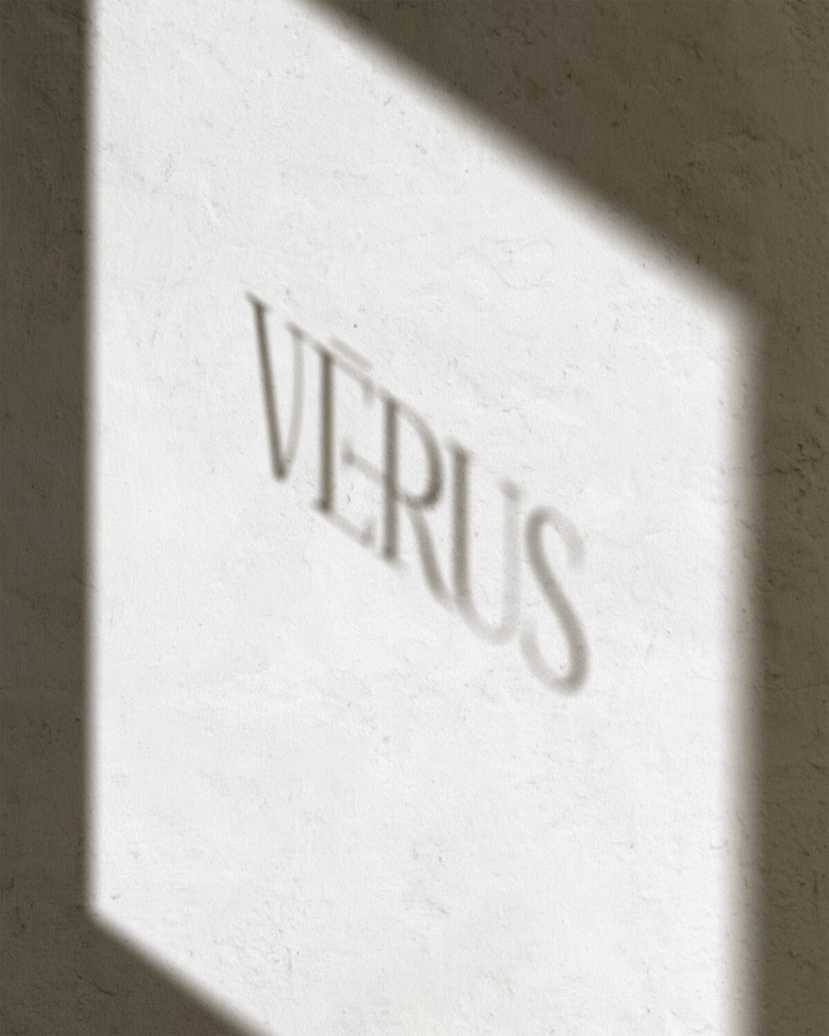 Minimalistisch schaduwlogo van Studio Vérus op muur