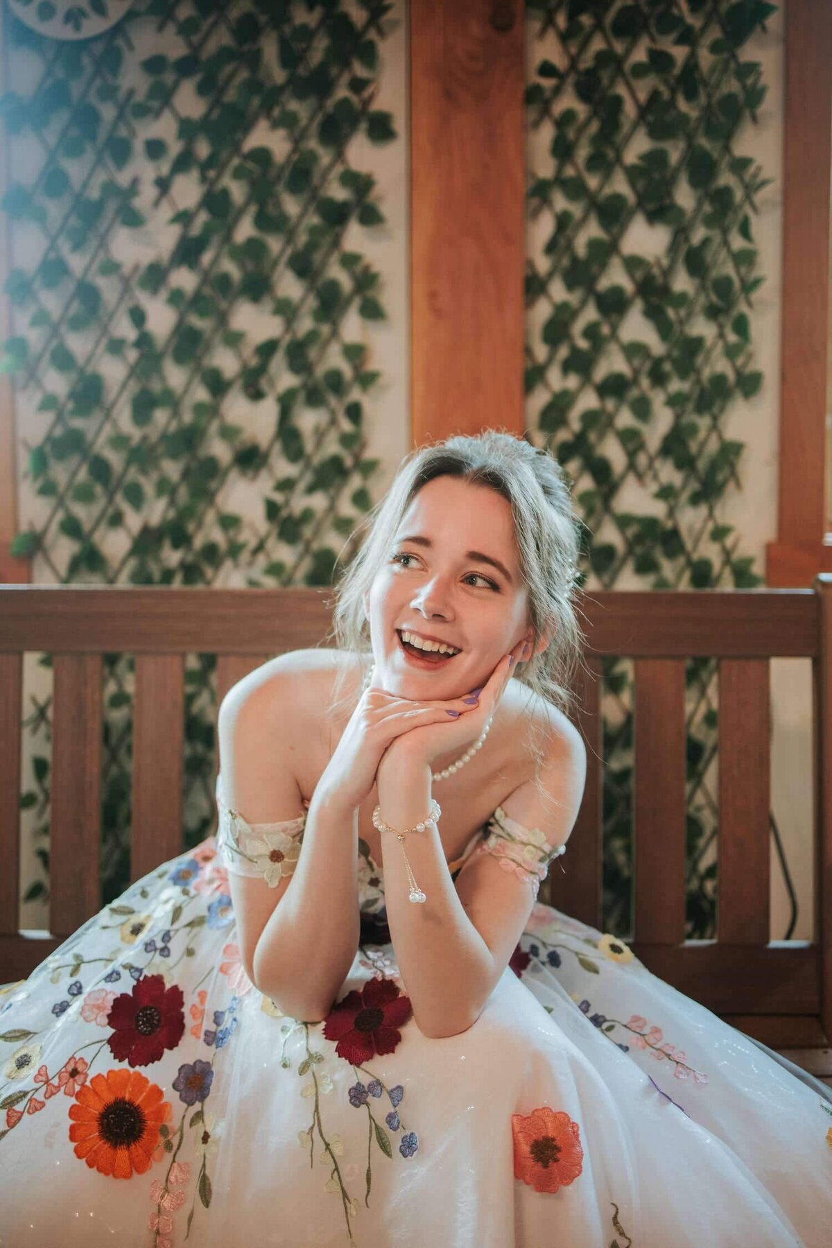 Bride smiles happily while sitting on bench before the first look at the Rose Bank Winery