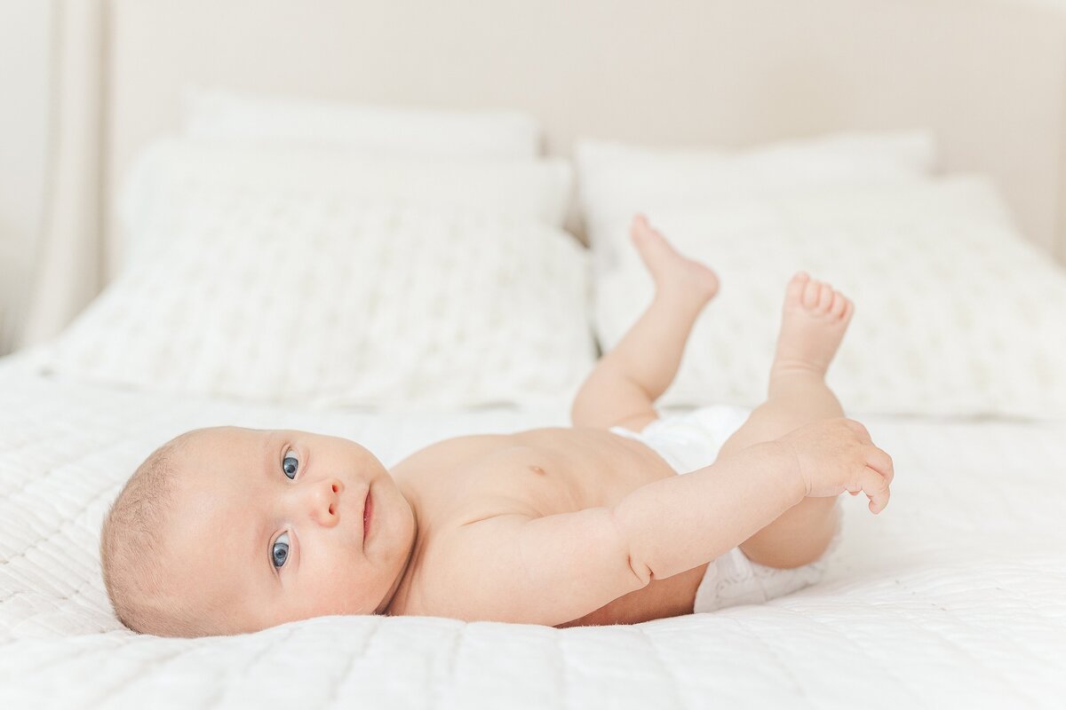 baby lays on bed during in home newborn photo session with Sara Sniderman Photography  in Wellesley Massachusetts