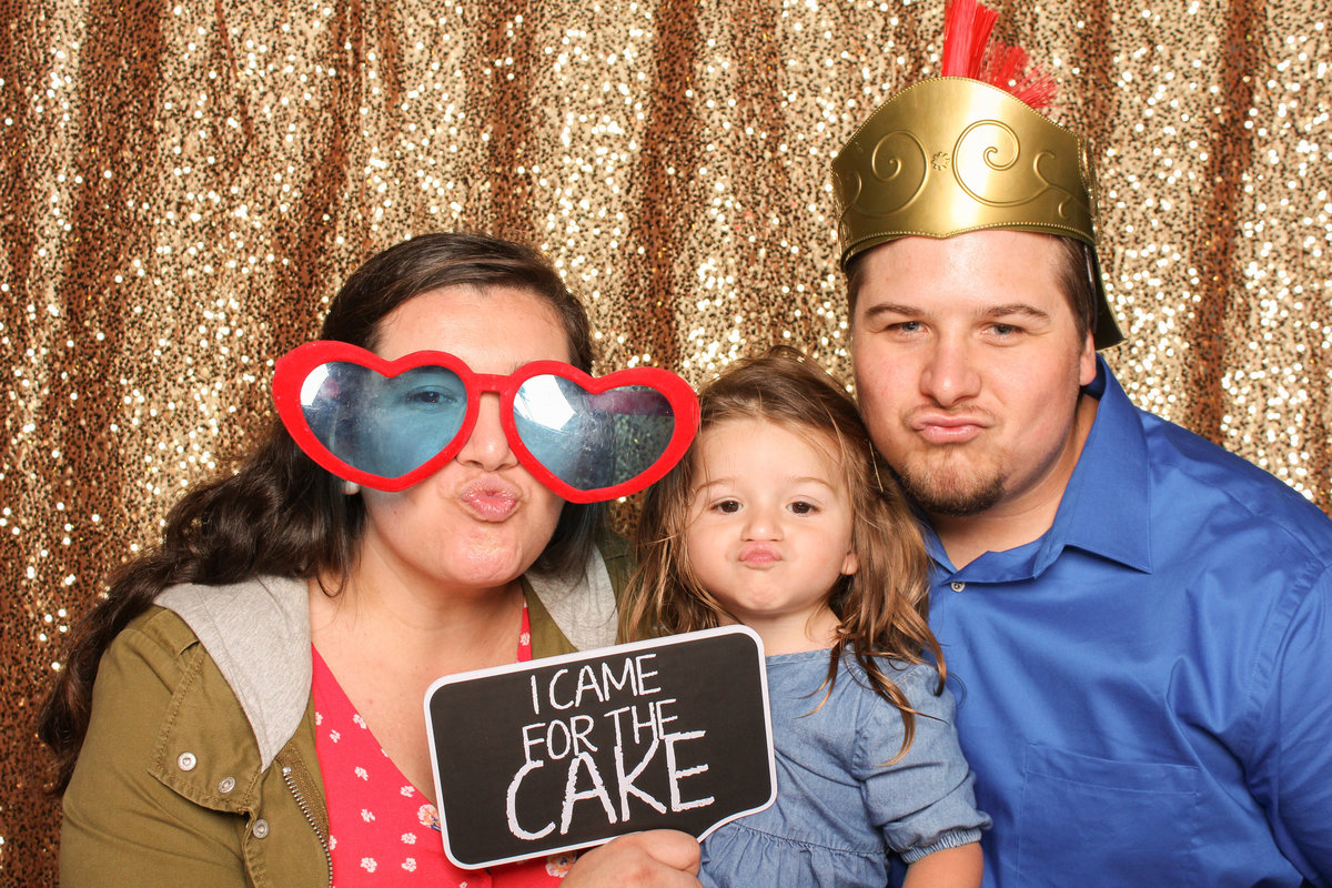 Man, Woman and their Daughter make faces at the photo booth camera at a wedding reception