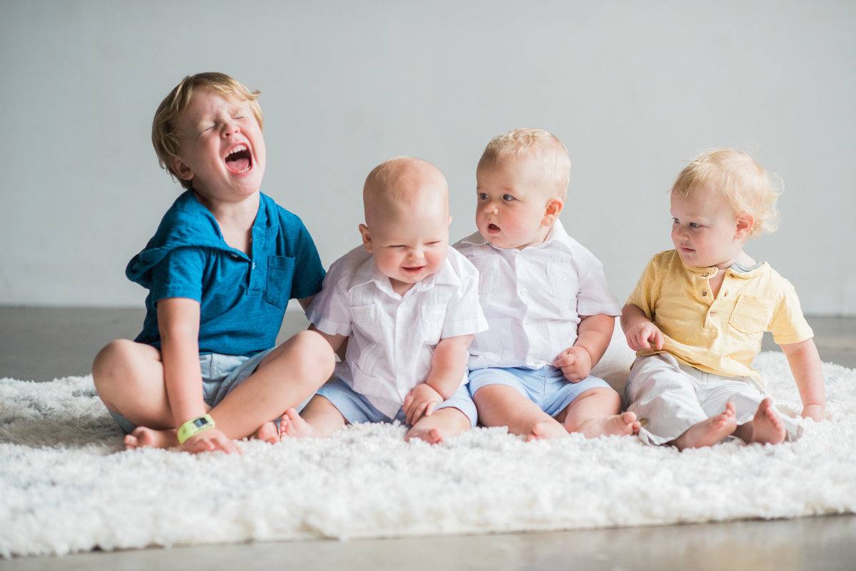 four little boys sitting and laughing including twin babies