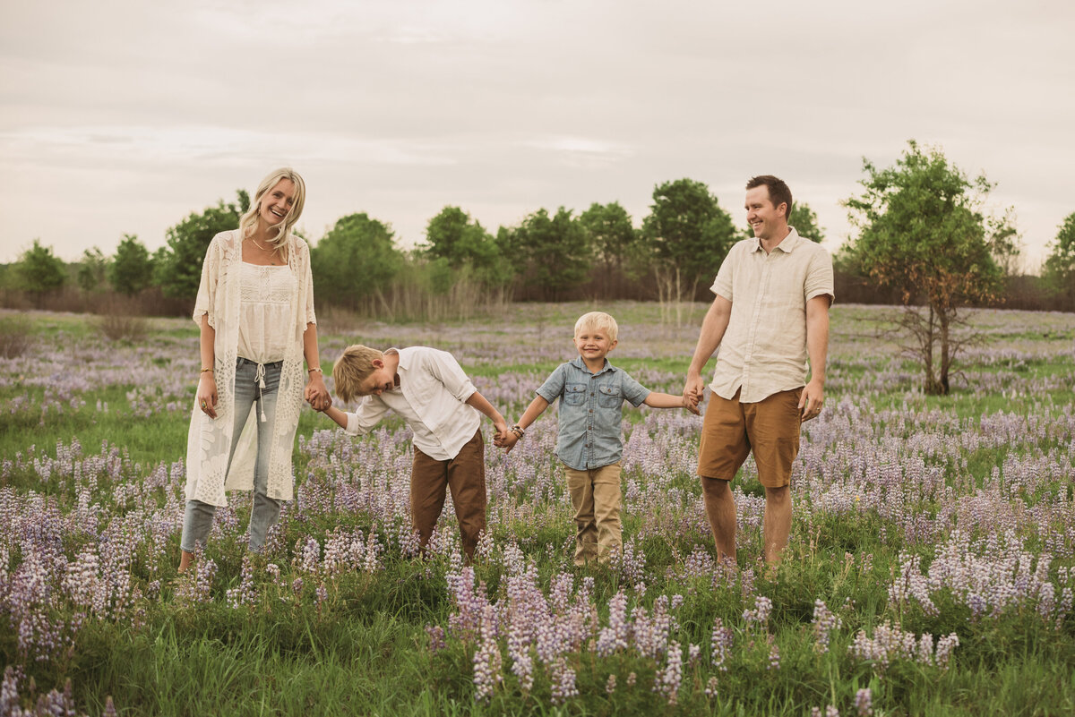 family laughing in field holding hands