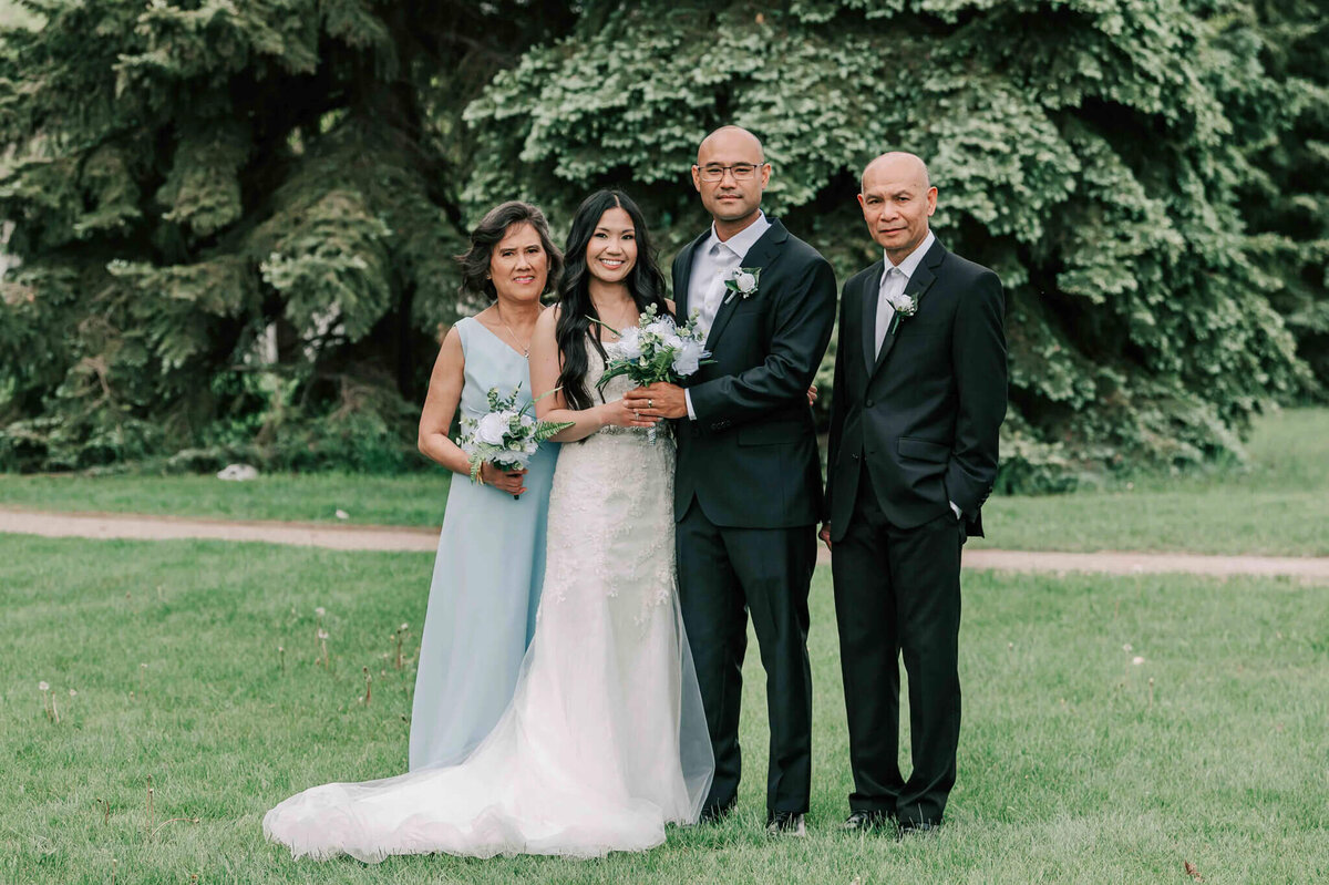 Bride and groom stand with bride's parents.