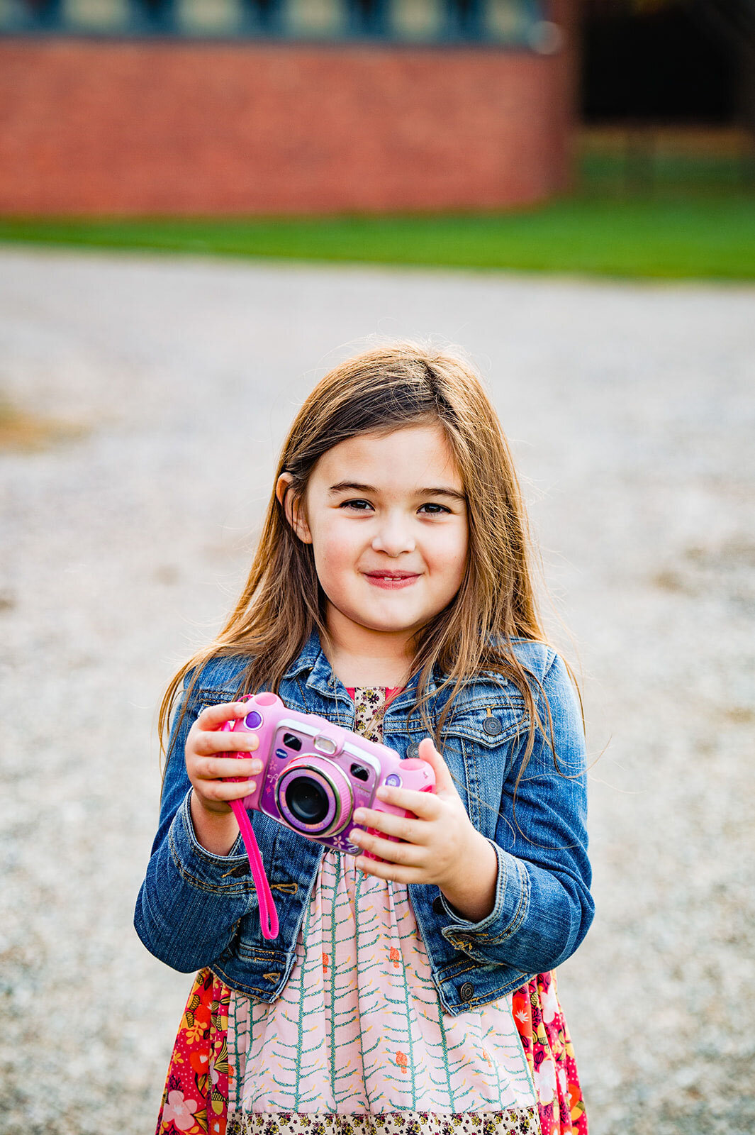young girl holding pink camera