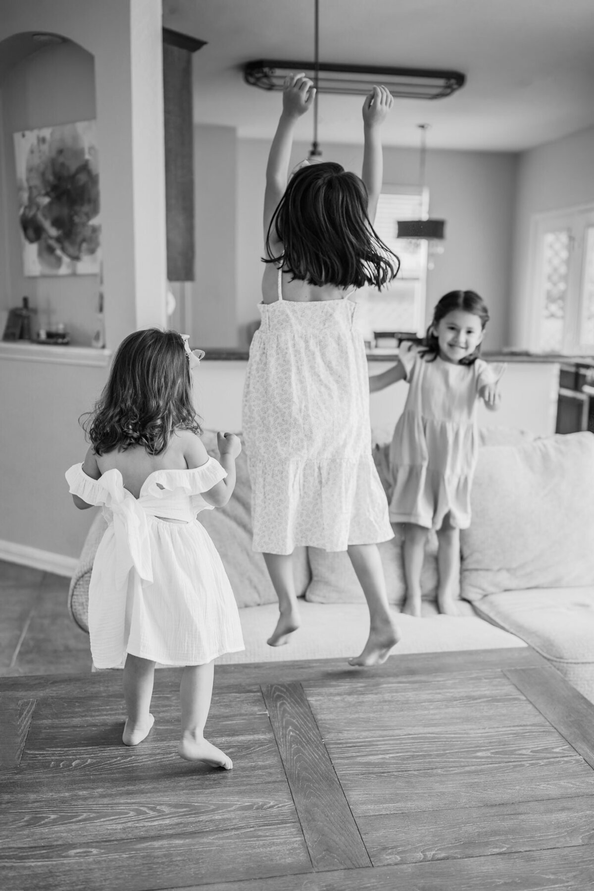 Black and white image of three young girls dancing on their coffee table.