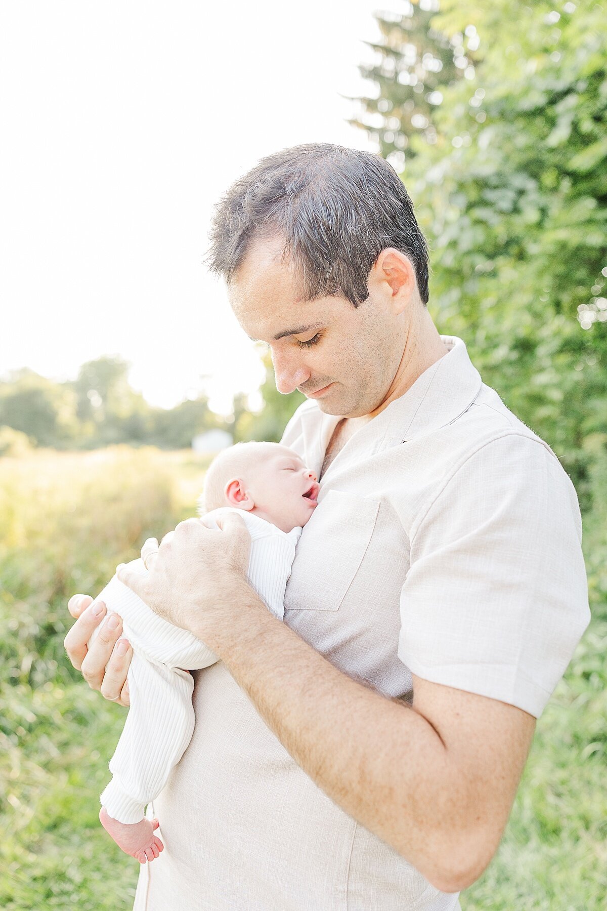 dad holds baby during outdoor newborn photo session at Heard Farm in Wayland Massachusetts with Sara Sniderman Photography