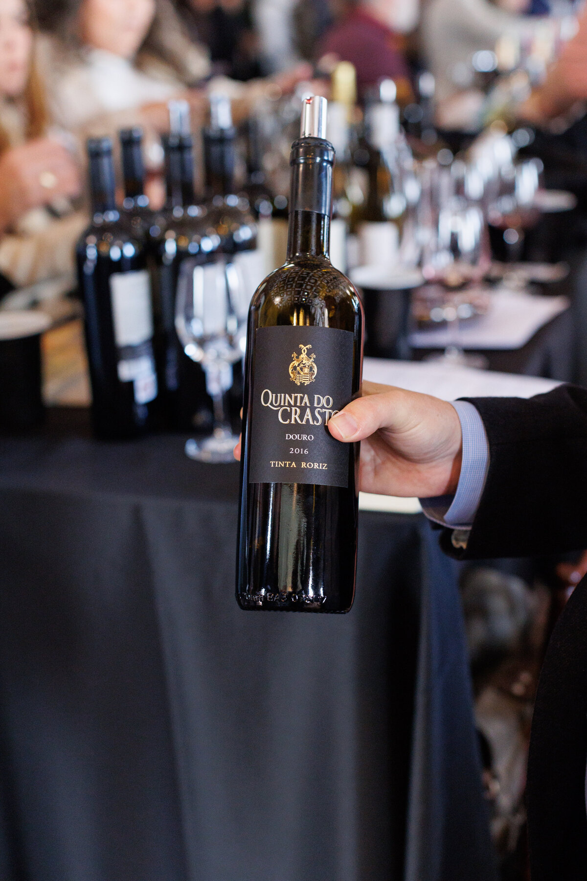 A hand showcasing a bottle of Wine