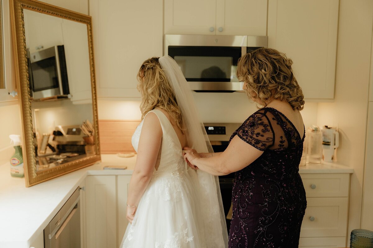 Mother helping the bride with her wedding dress.