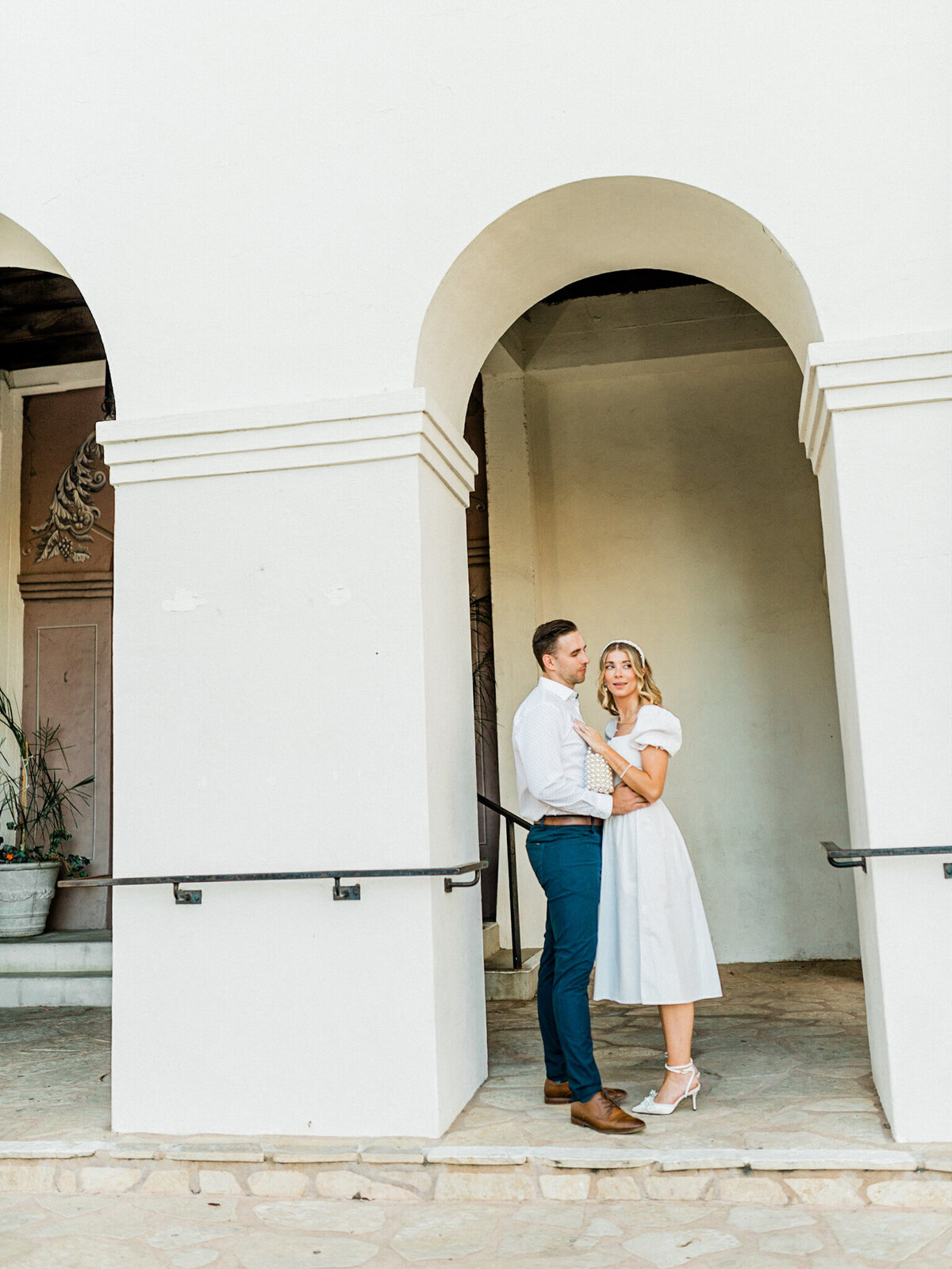Romantic engagement photo beneath classic white arches—elegant, timeless, and full of California charm.