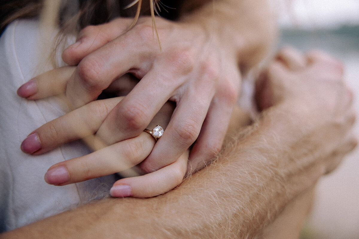 Couple squeezes hands together for candid ring shot for their engagement photo session in Nashville, TN.