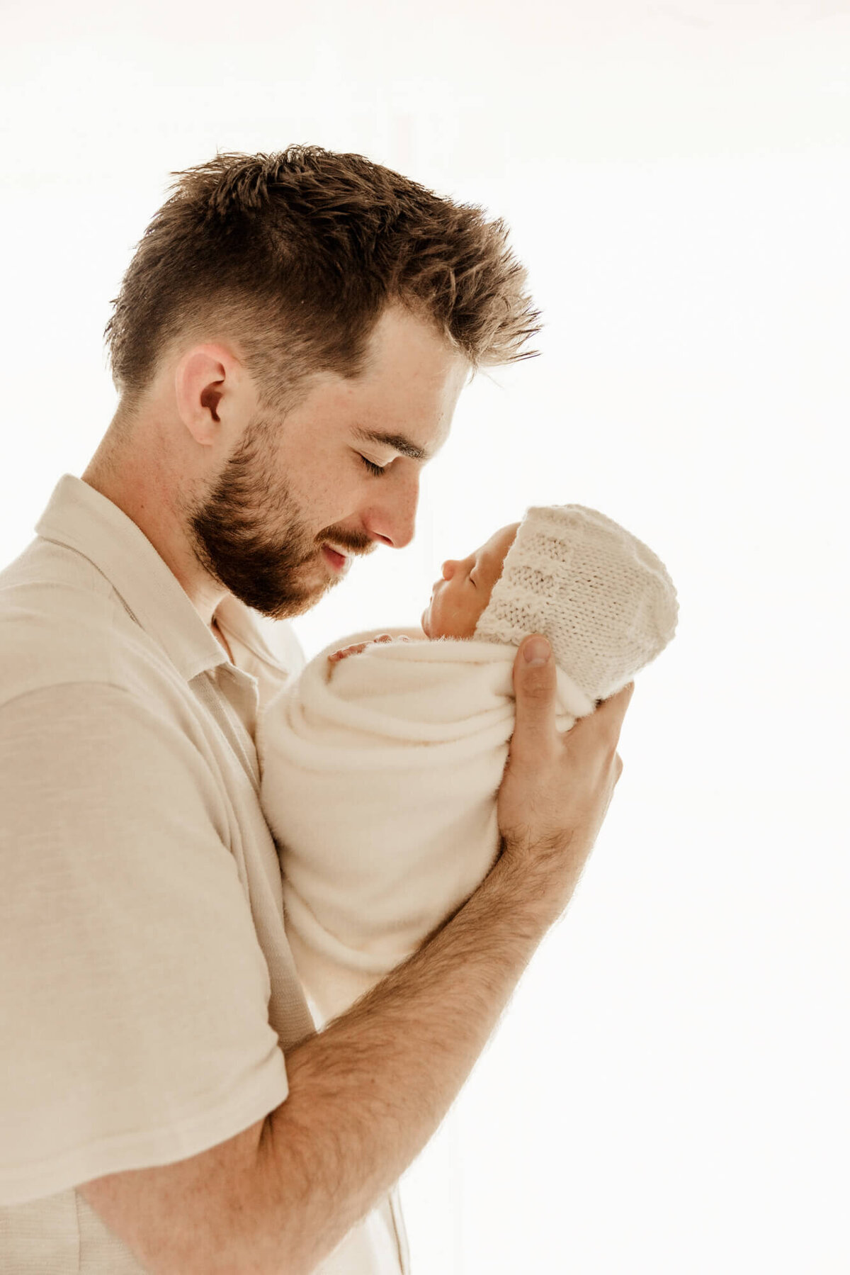 Father holds his daughter in his arms close to his face and looks at her as she sleeps.