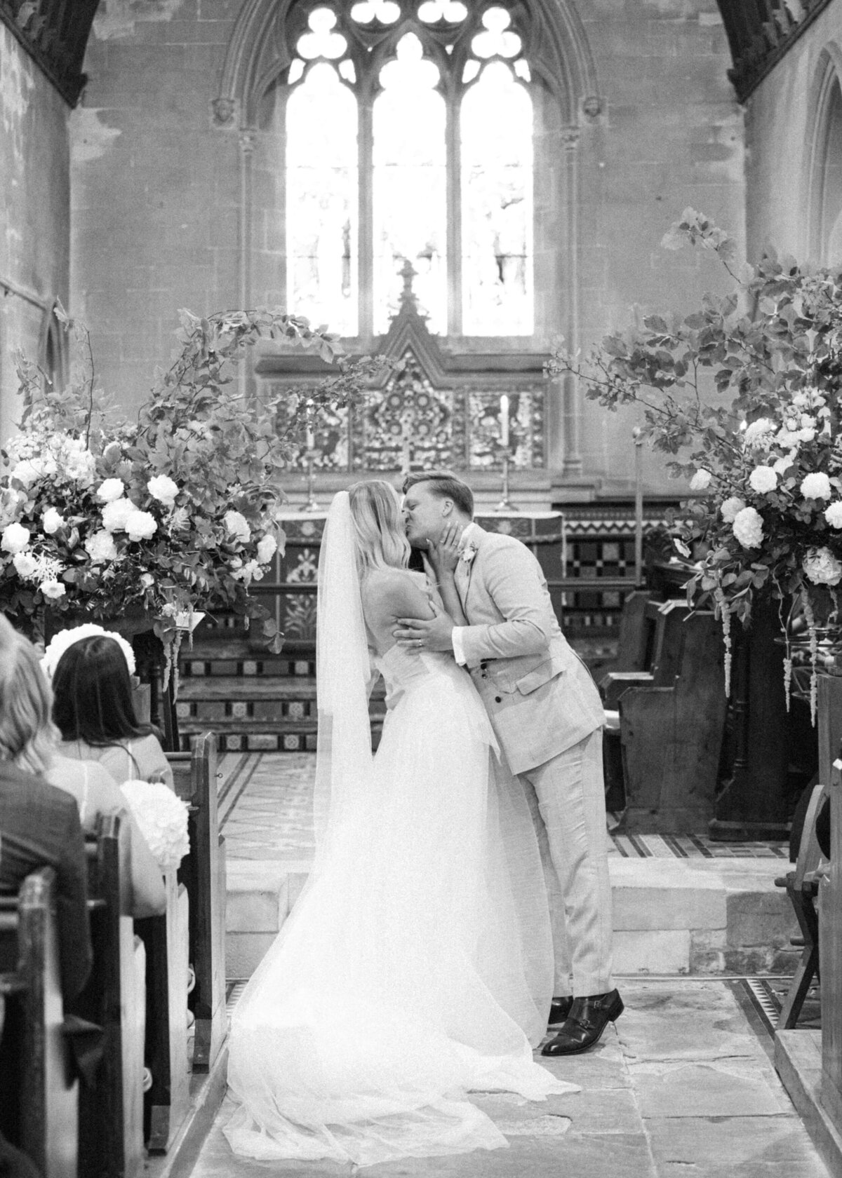 chloe-winstanley-weddings-church-ceremony-cotswolds-kiss-black-white