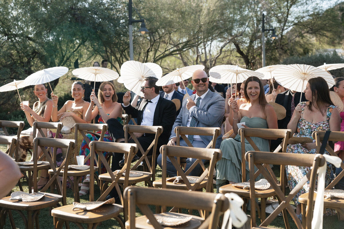 Guests smiling holding parasols at wedding ceremony at El Chorro in Arizona