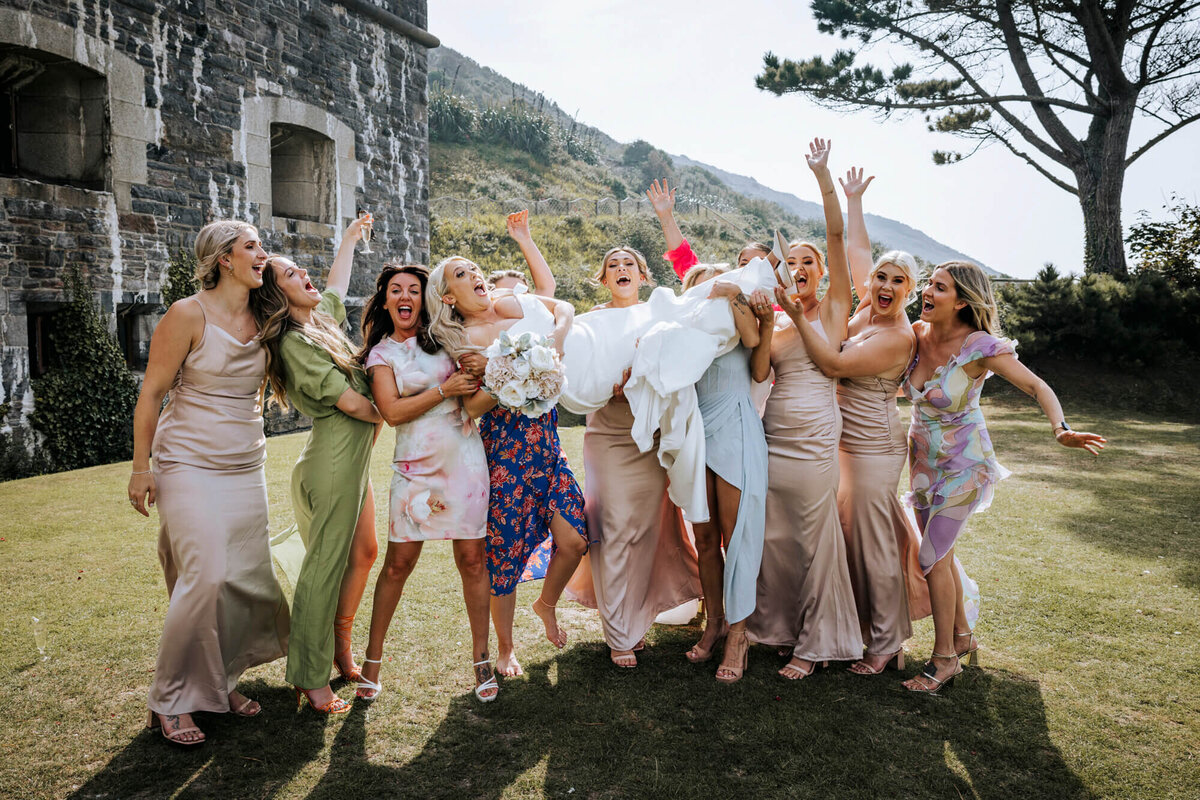 A group photo of the bridesmaids holding the bride in the air