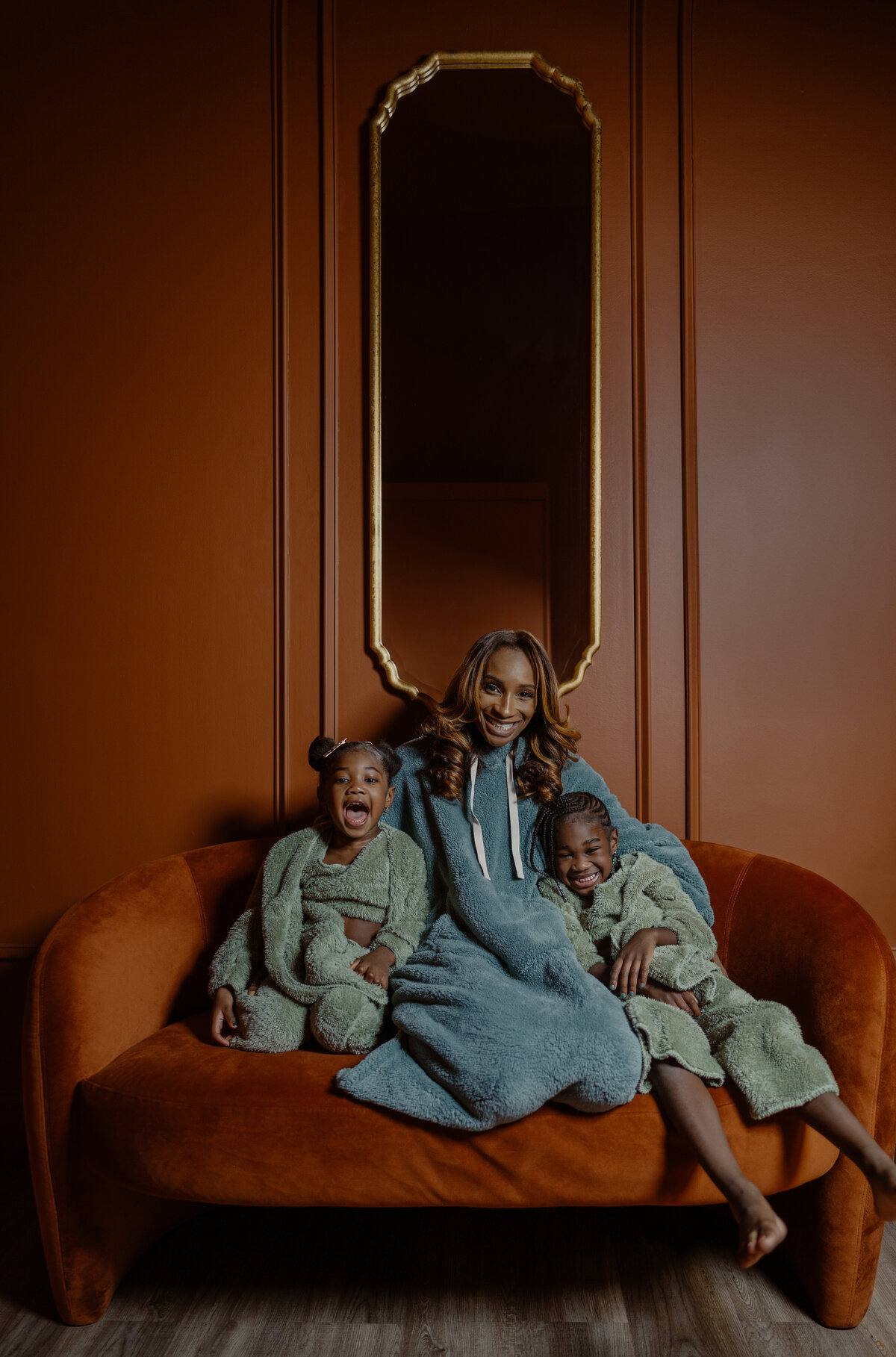 A fun family portrait of mother and daughters gathered on a couch, highlighting warmth and closeness during an NYC family session.