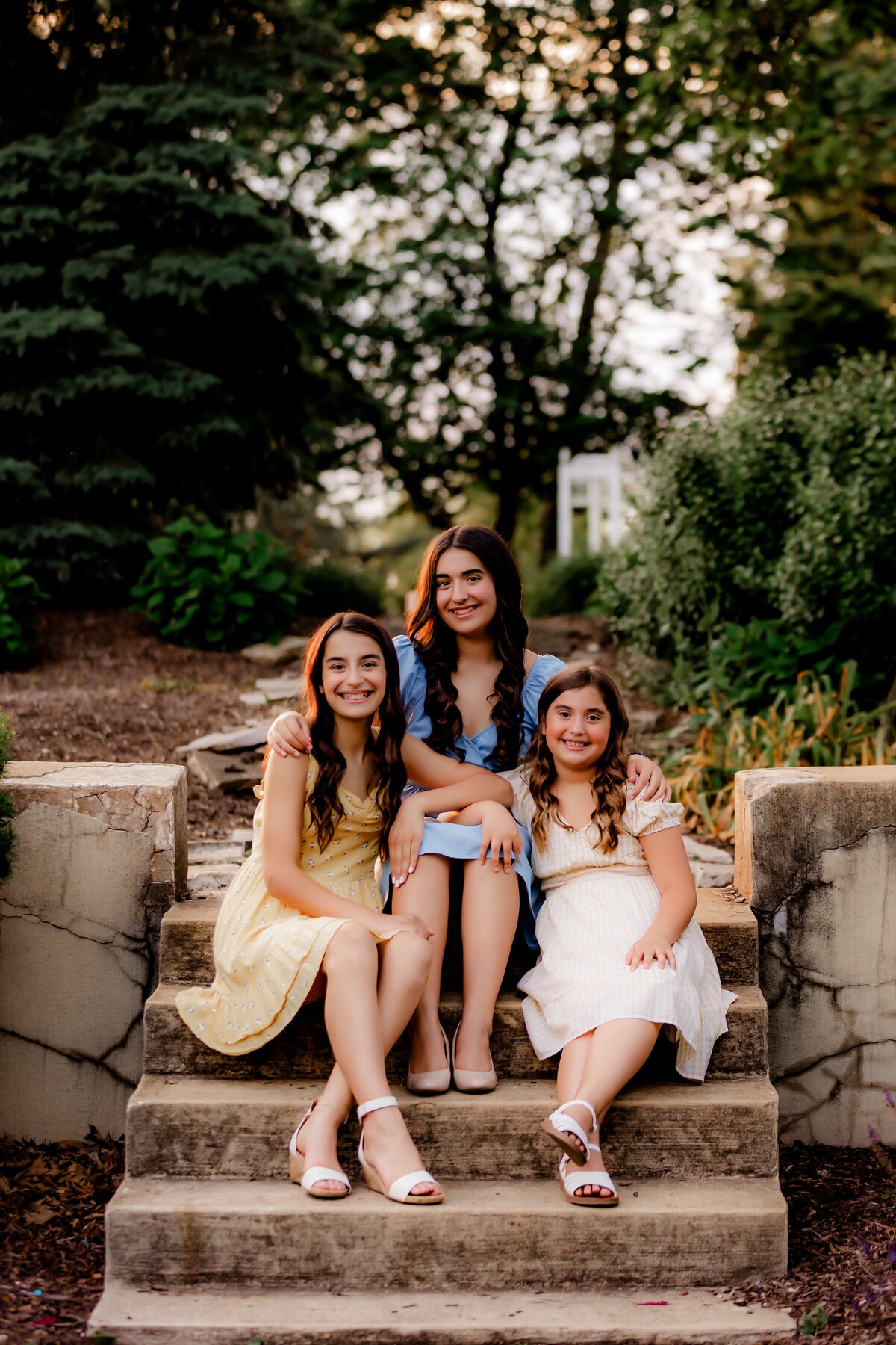 A portrait of three sisters sitting on steps.