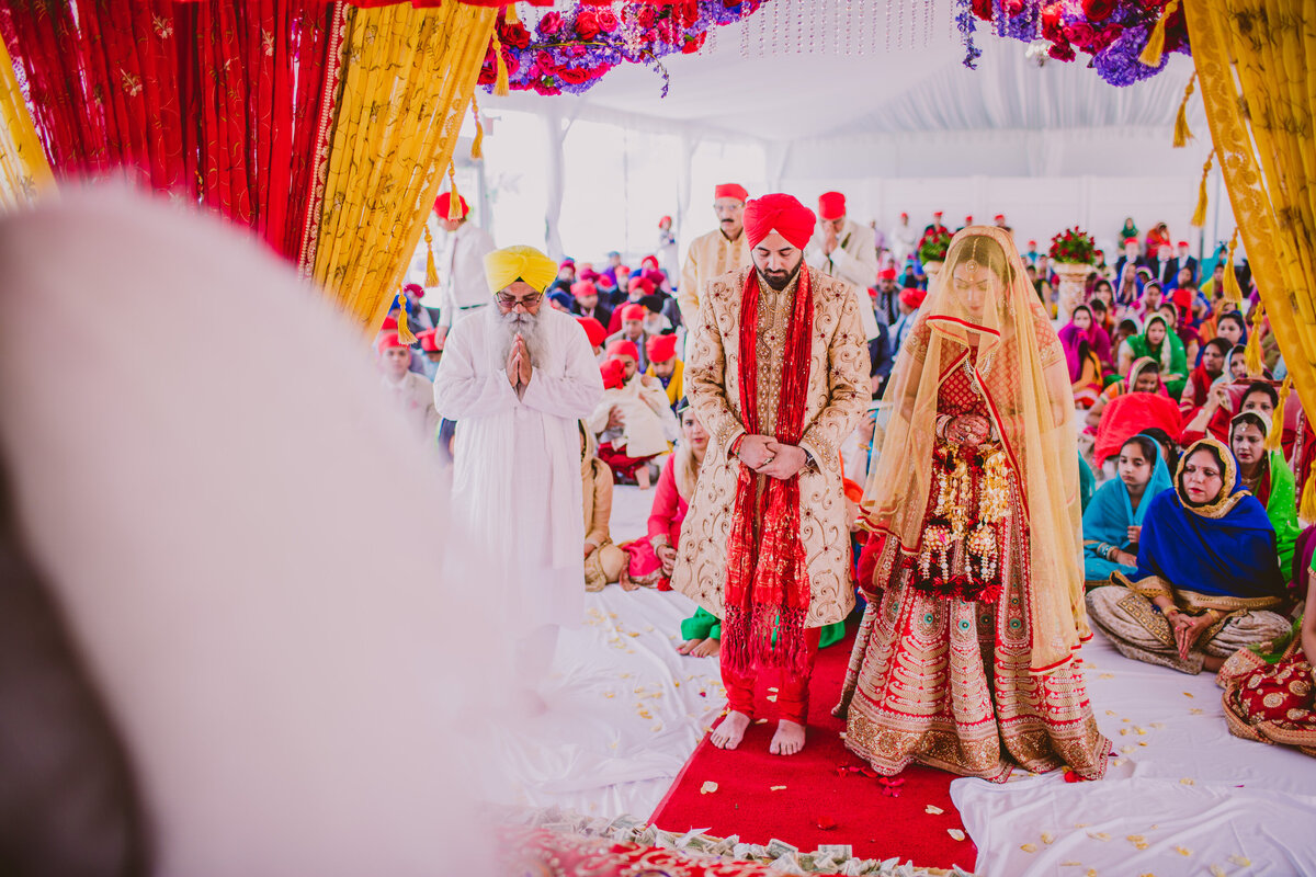 sikh bride and groom standing during their anand karaj wedding ceremony in a tent country club in new jersey