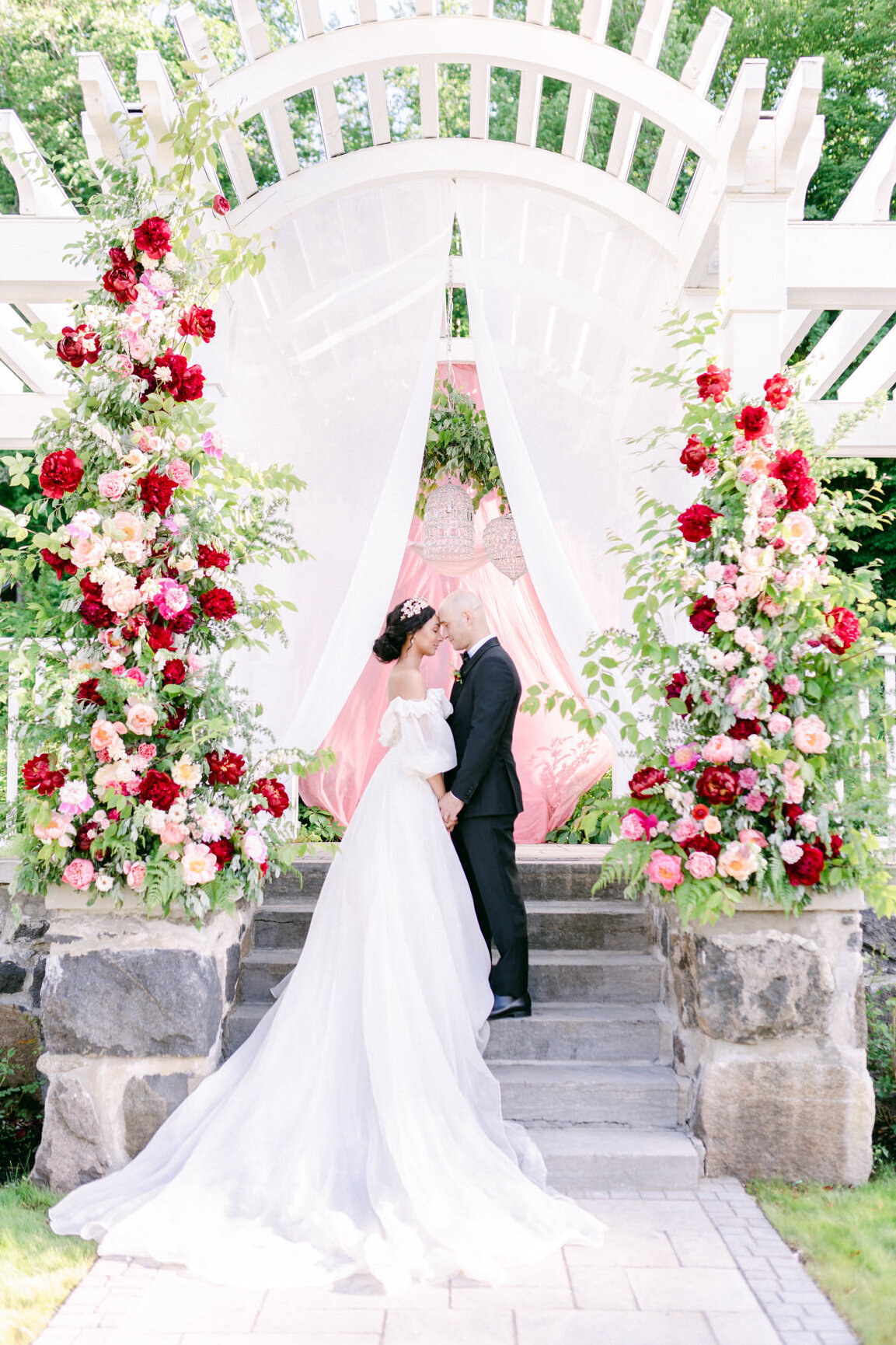 A bride and groom embrace surrounded by pillars of flowers at their wedding ceremony at Stonehaven Manor.