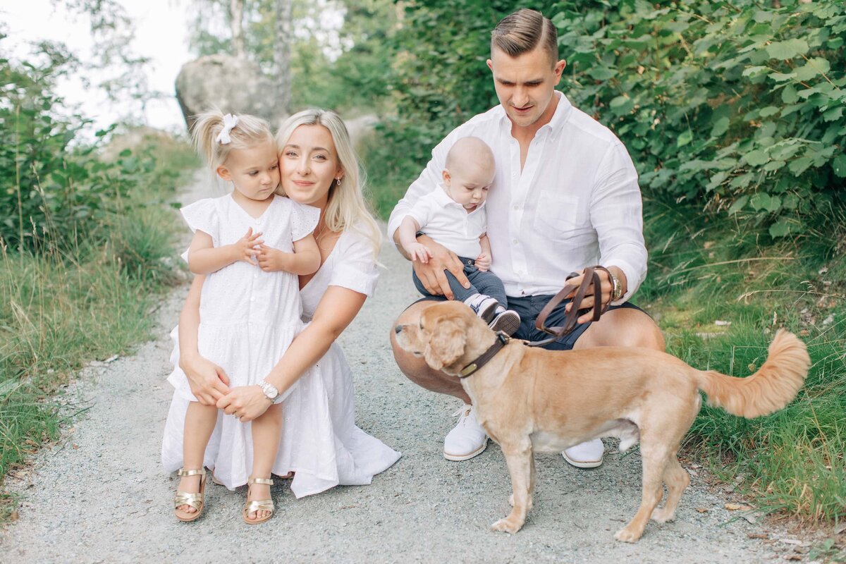 En familj och deras hund på en grusgång på sommaren