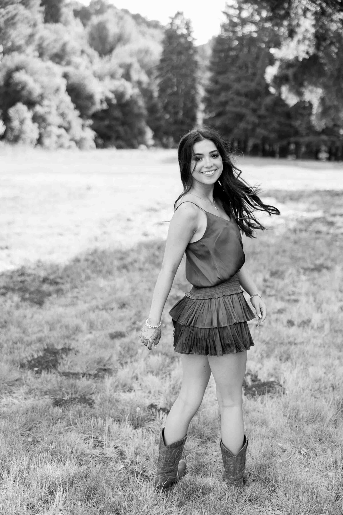 Black and white photo of a brunette girl looking back over her shoulder and swinging her hair back