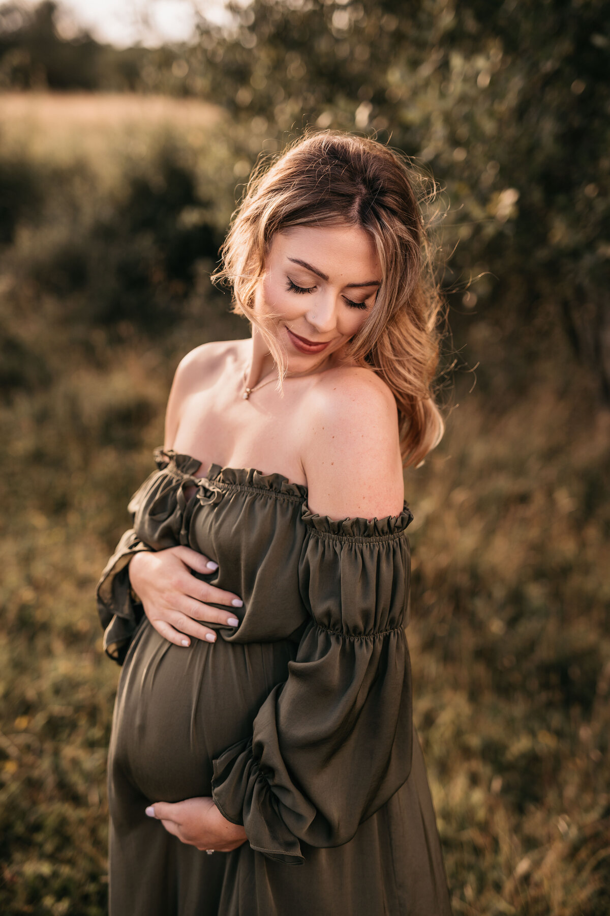 Photo of a pregnant woman in a green dress outdoors at sunset