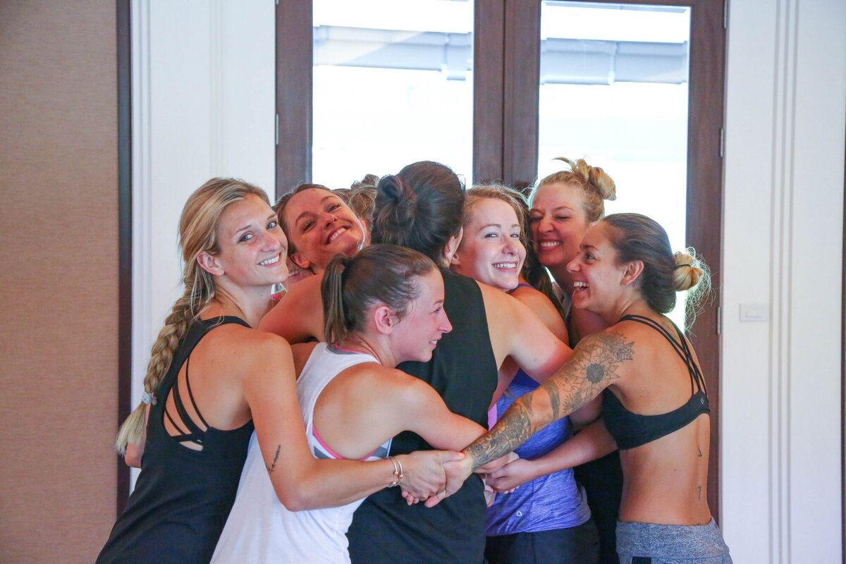 group of women on a yoga retreat having a group hug