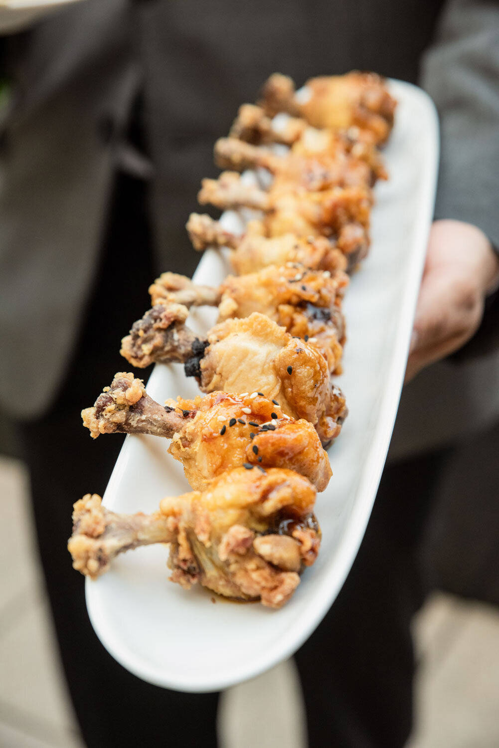 A person is holding a plate of fried chicken wings