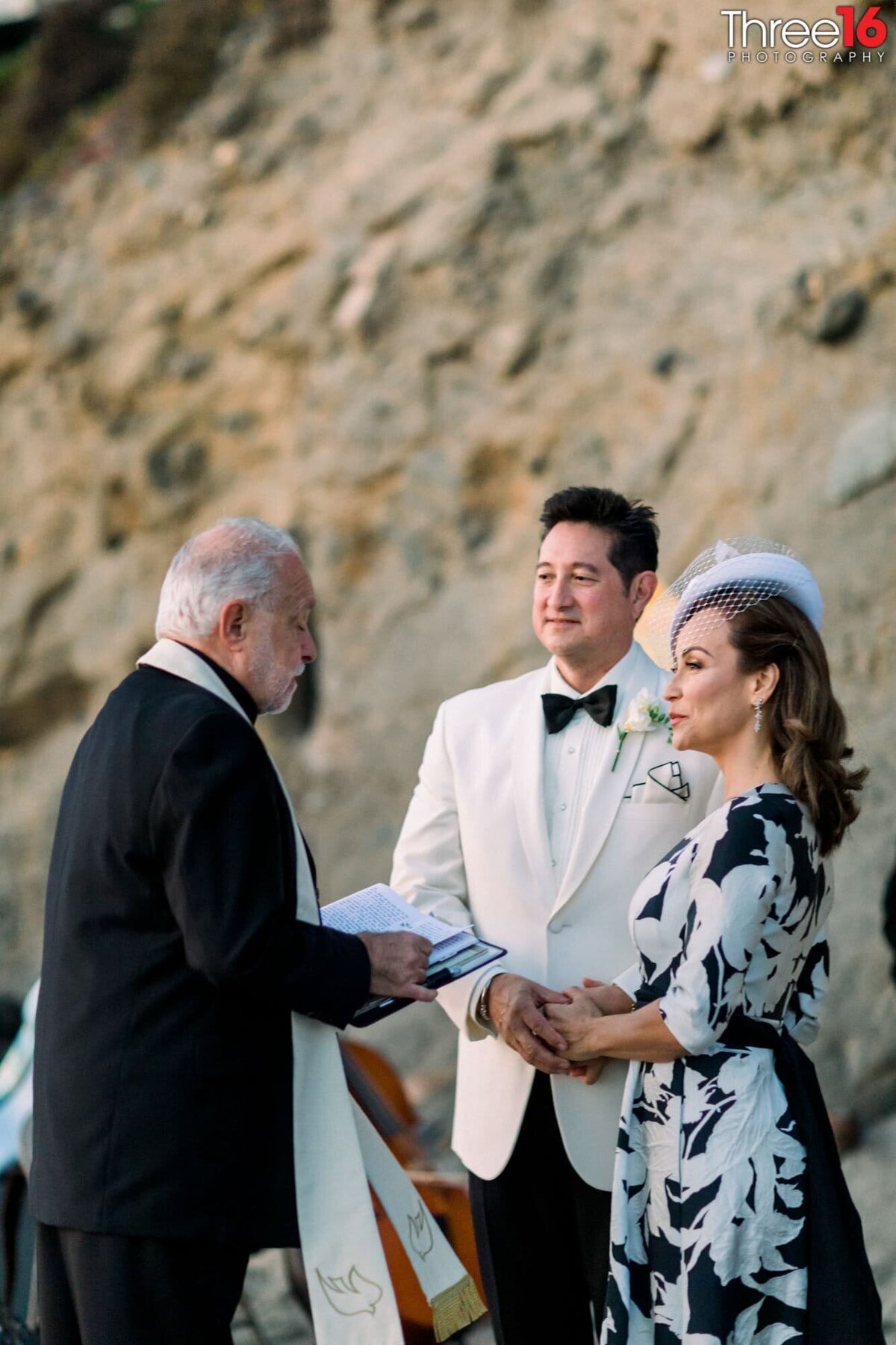 Bride and Groom hold hands as they listen to the officiant during an elopement ceremony on the beach