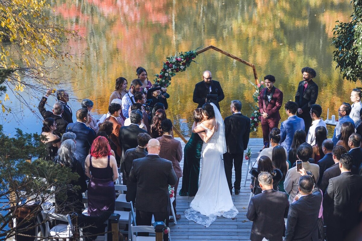 Bride and groom standing together at the altar with the lake reflecting behind them.