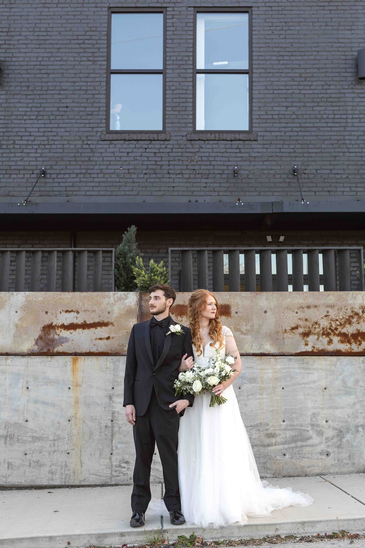 Bride and groom holding each other looking opposite directions