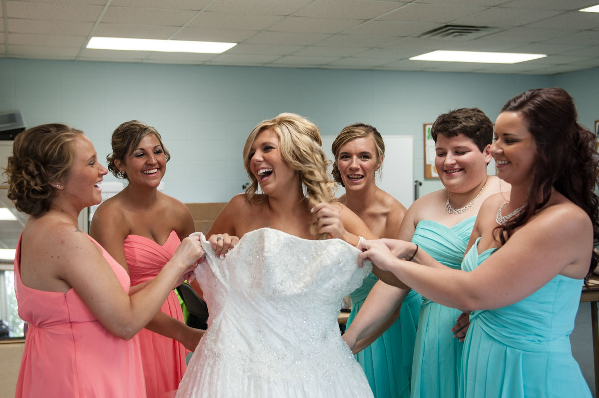 bride getting dressed with bridesmaids