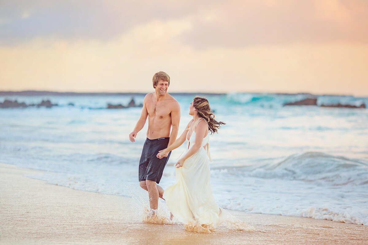 Fun couple runs toward the camera during their Wailea engagement photography session with Love + Water