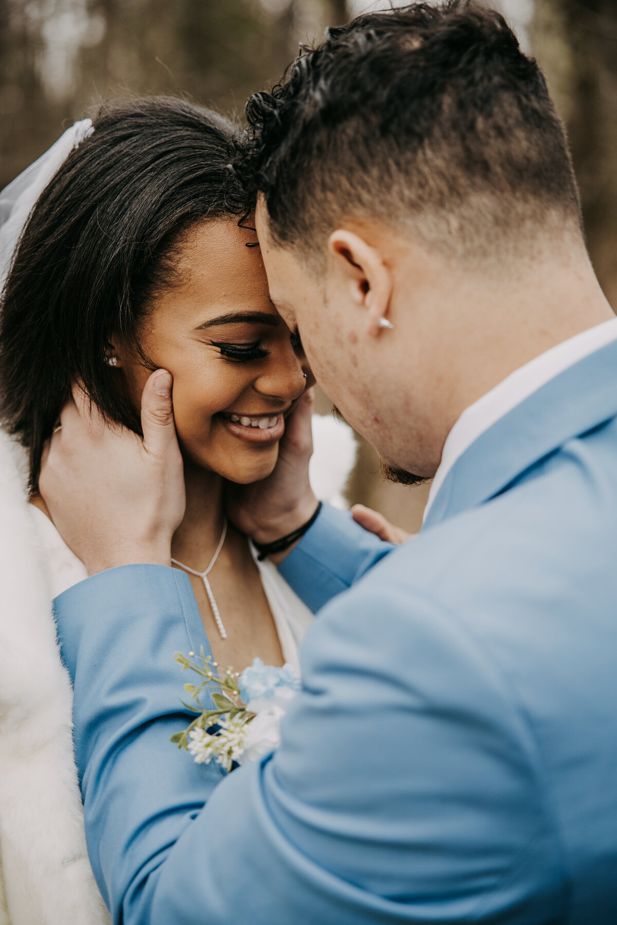 Close-up of a bride smiling as her fiancé gently holds her face, capturing an intimate and joyful moment.