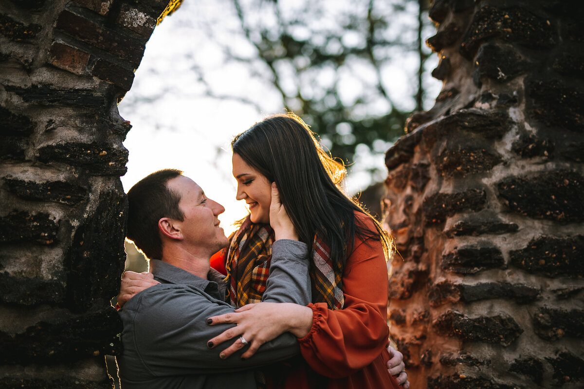 Coastal couple embrace at stone wall by the coast.