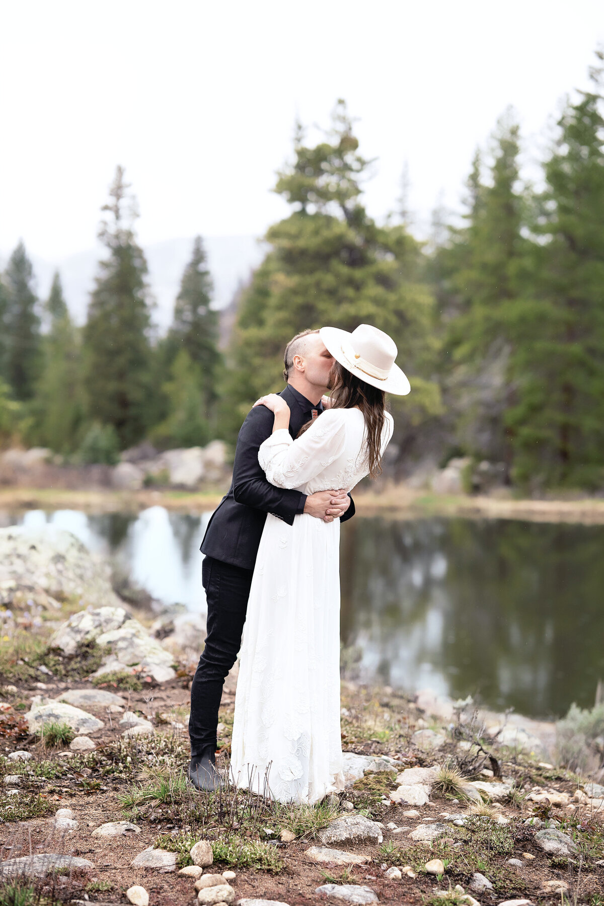 Bride and groom kissing near a beautiful lake at Beyul Retreat in Aspen, Colorado,