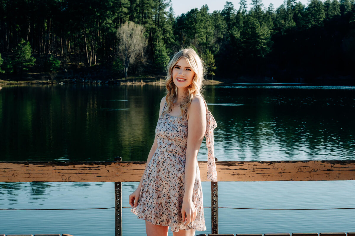 Girl poses in front of lake and forest in Prescott senior photos
