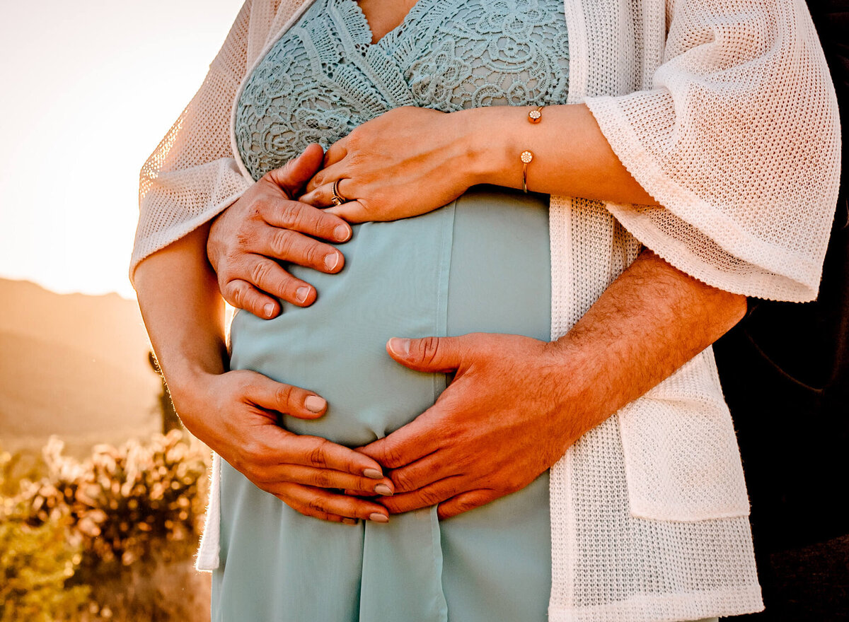 photograph of mom and dad placing hands over their baby-to-be during maternity session with Arizona photographer