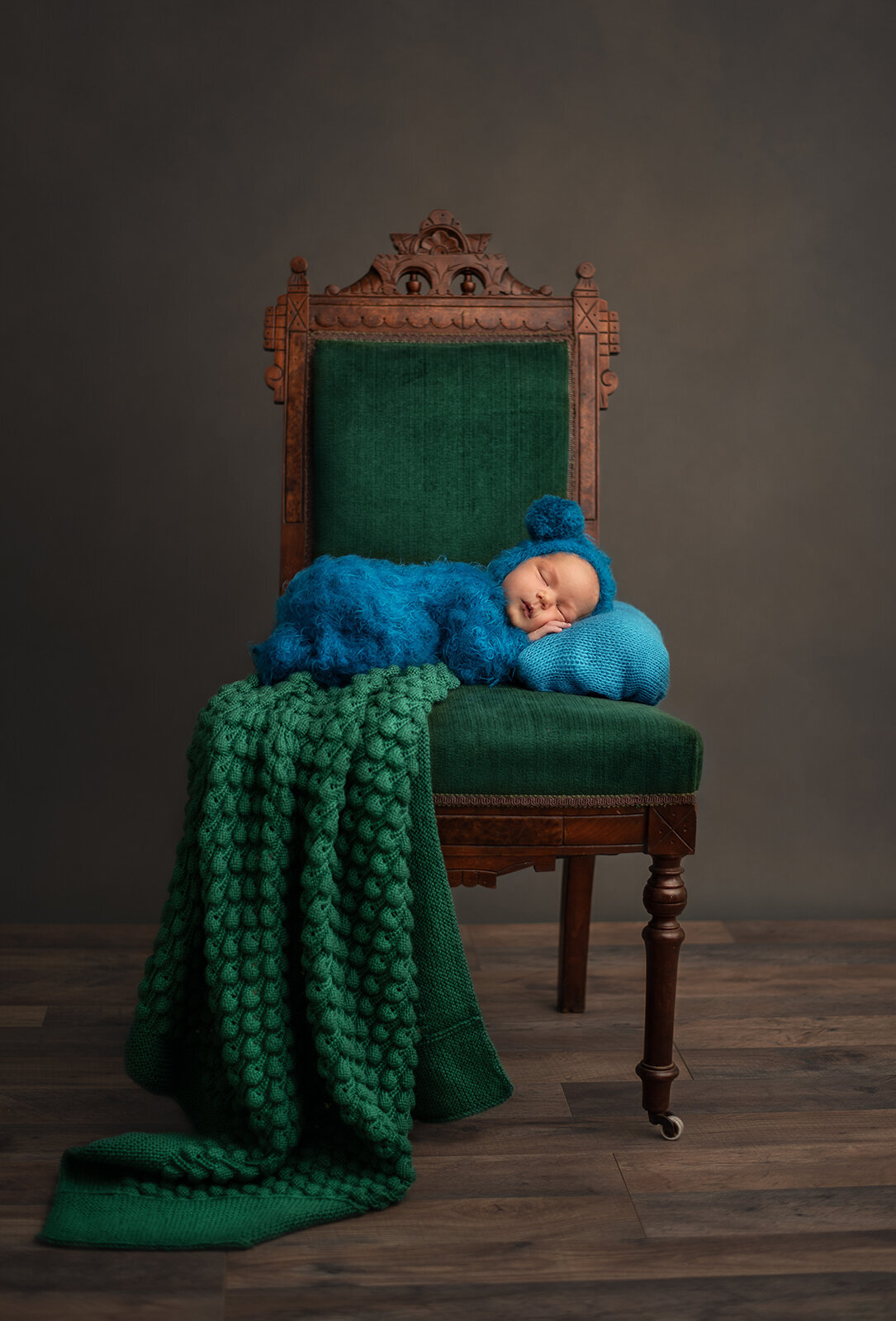 baby sleeping on green chair in blue outfit at st. louis newborn photo session