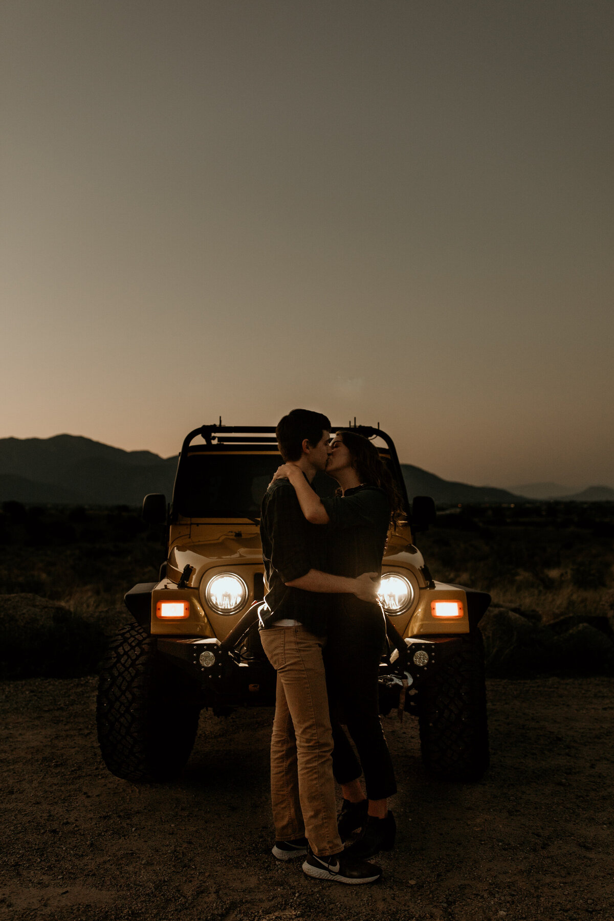 engaged couple kissing in front of jeep at sunrise in Albuquerque