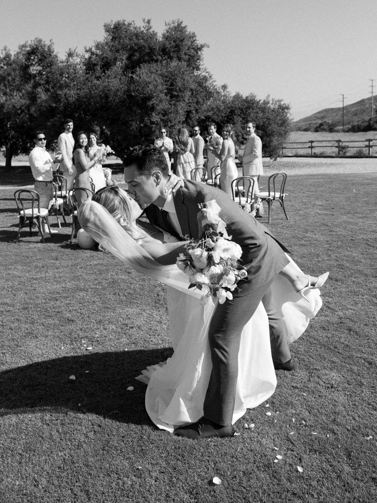 Bride and groom sharing a passionate kiss at the end of the aisle, captured by a La Jolla wedding photographer.