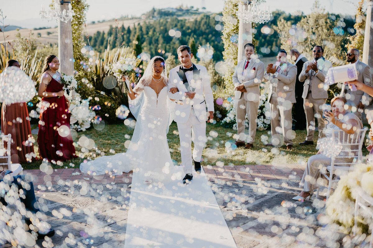Newlyweds walking through bubbles after the ceremony at Tenuta Corbinaia, romantic wedding in Tuscany.