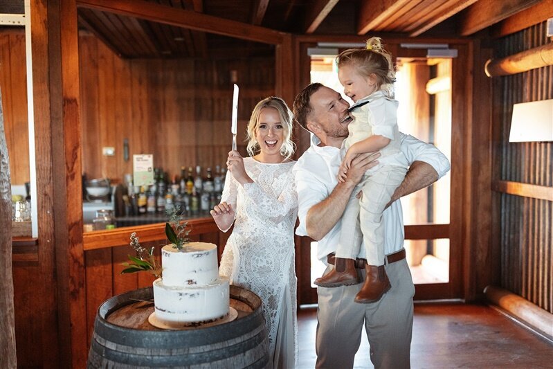 oin Maddi & Jeremy, along with their adorable little one, as they celebrate their special day with joy and laughter around their stunning wedding cake.
