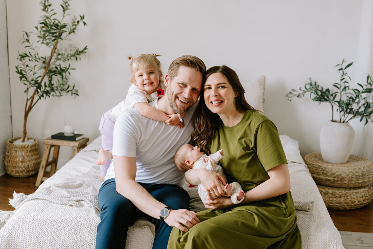 Parents, a toddler, and a newborn baby pose for family photos in Calgary, Alberta