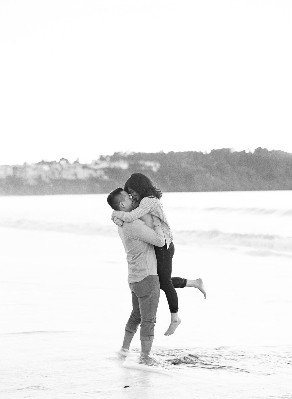 Strong man lifts his partner on nearshore waters at a beach.