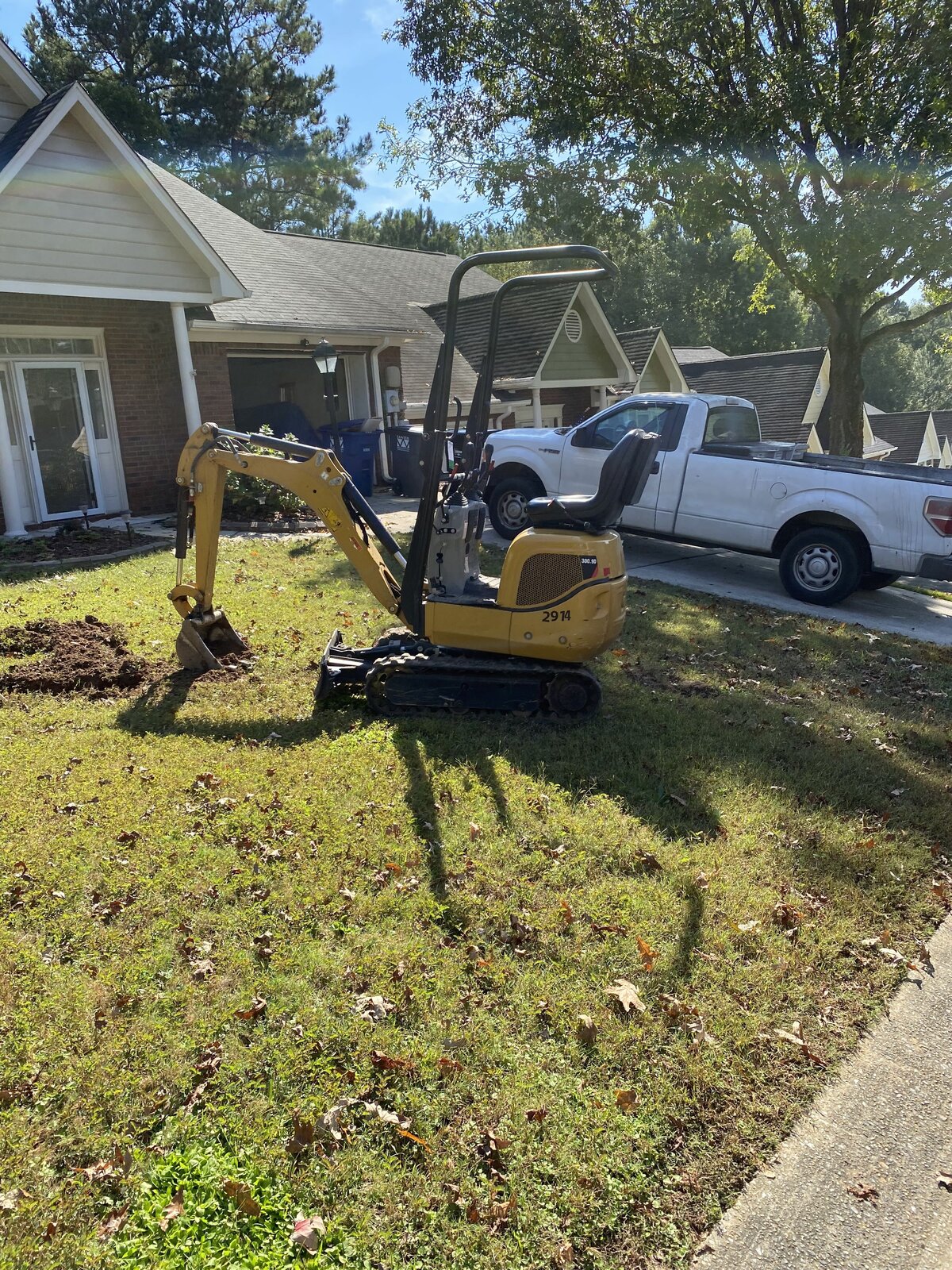 yellow-machinery-in-front-yard-next-to-white-truck