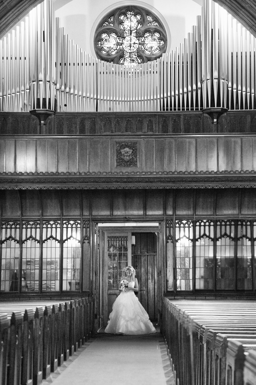 black and white wedding photo of bride walking down the aisle by herself